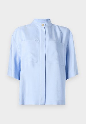 Šviesiai mėlyna trumpomis rankovėmis palaidinė su mandarinų koliu, dviem priekinėmis kišenėmis, tekstūruotu audiniu ir sagų uždarymu.