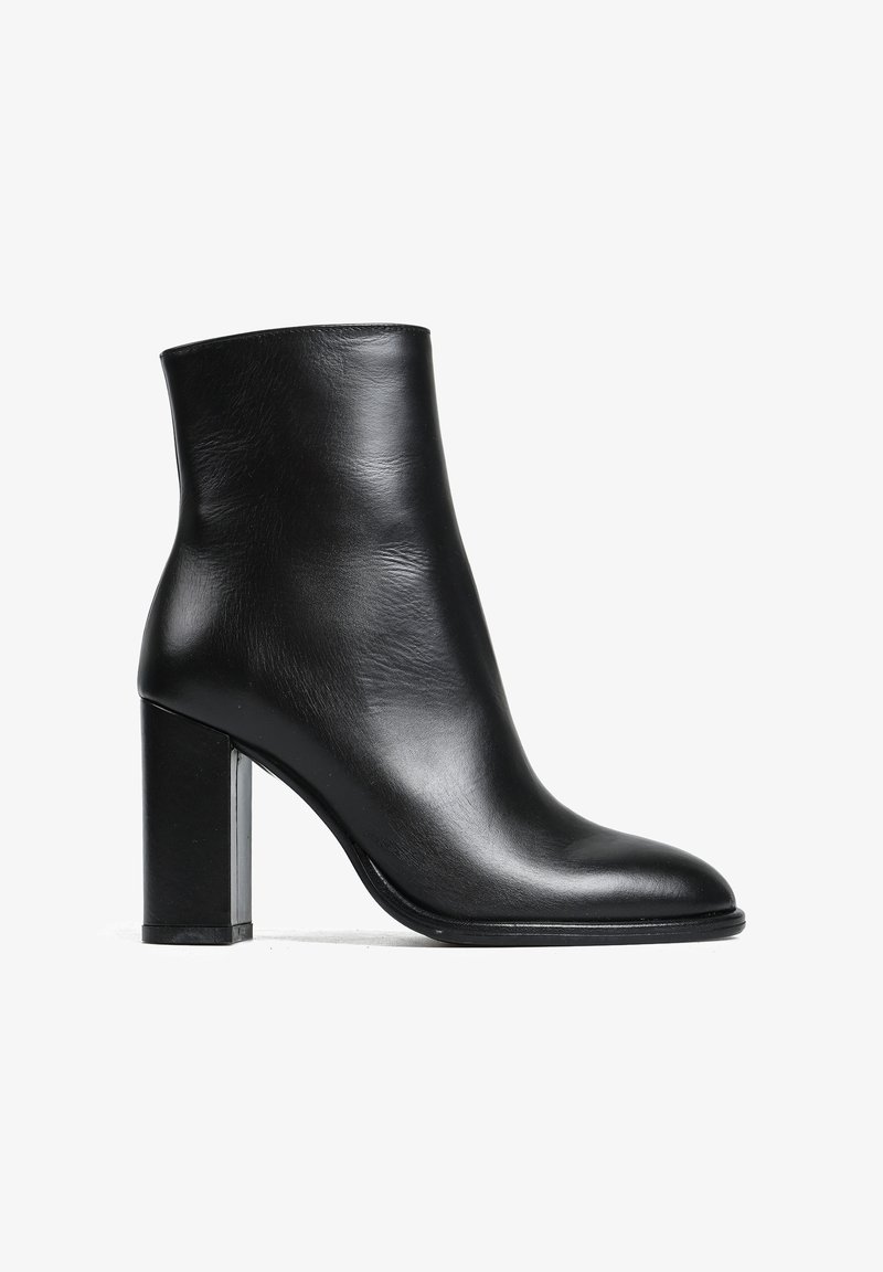 Czarna skórzana botka sięgająca kostki o gładkim wykończeniu, z wydłużonym noskiem i masywnym obcasem. Minimalistyczny design bez widocznych elementów metalowych czy ozdób.