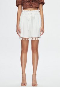White shorts made of lightweight fabric with a gathered waistband and tie; features a scalloped hem with circular accents.