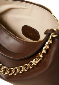 Borsa a mano in pelle marrone con una texture liscia, dotata di una tracolla in catena dorata e un interno beige. Il marchio è visibile su una patch in pelle.