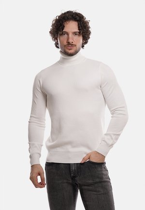 Maglione bianco a collo alto con un motivo testurizzato, design aderente e maniche lunghe, abbinato a jeans scuri. Stile semplice e moderno.