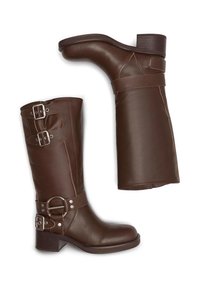 Cizme din piele maro, până la genunchi, cu toc bloc, dotate cu catarame metalice, detalii de cusătură și o textură netedă.