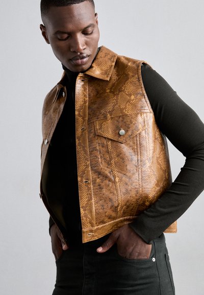 Gilet en cuir imprimé serpent marron avec un col, des boutons-pression et des poches avant, porté sur une chemise noire à manches longues.