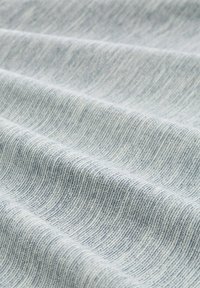 Jasnoniebieski materiał o miękkiej, teksturowanej powierzchni, z subtelnym wzorem w paski i różnymi odcieniami niebieskiego w całej strukturze.