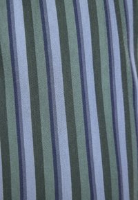 Tejido a rayas con líneas verticales en verde oscuro, verde claro y azul. Textura suave con rayas de diferentes anchos.