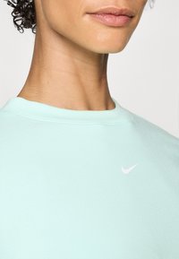 Mjesečevzeleni Nike dukserica s okruglim izrezom. Sadrži mali bijeli Nike logo na prsima. Mekani materijal s glatkom teksturom.