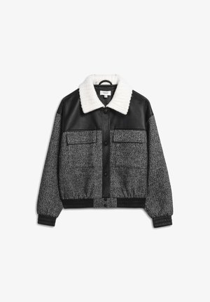 Giacca corta nera e grigia con colletto bianco a coste, chiusura frontale a bottoni, due tasche sul petto e polsini e orlo elasticizzati.