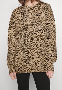 Sudadera de estampado de leopardo en tono marrón claro con manchas negras, con un corte relajado, mangas largas y puños de canalé. Tejido suave con una textura lisa.