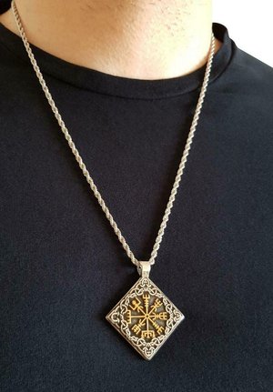 Collana in argento con un pendente a forma di diamante, decorato con intricati simboli nordici in oro e dettagli a motivo circolare.