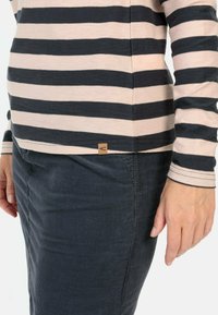 Gestreepte blouse met lange mouwen in roze en marineblauwe horizontale strepen, gecombineerd met een donkere ribfluwelen broek. Bevat een klein bruin label op de zoom.