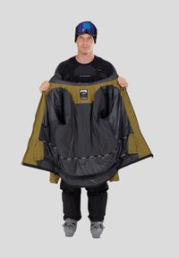 Lyžařská bunda s černým interiérem a olivově zeleným exteriérem; disponuje velkými kapsami, zipy a logem na hrudi.