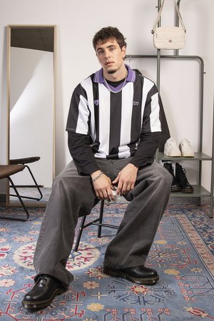 Black and white striped short-sleeve shirt, gray oversized pants, black lace-up shoes, silver accessories, with a mirror and bag in background.