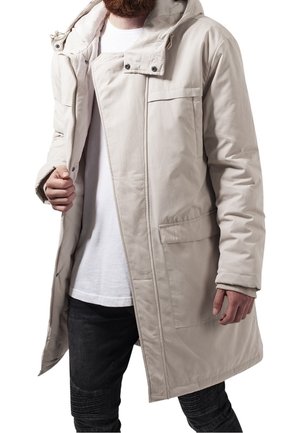 Light beige insulated coat with a hood, featuring a front zip closure, two side pockets, and a chest pocket. Smooth fabric texture.