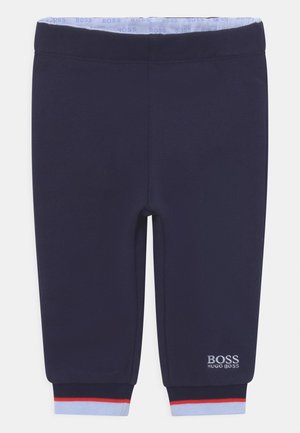 Marineblaue Baby-Jogginghosen mit elastischem Bund, hellblauem Innenfutter, rot-hellblauen gestreiften Bündchen und weißem Hugo Boss Logo am linken Bein.