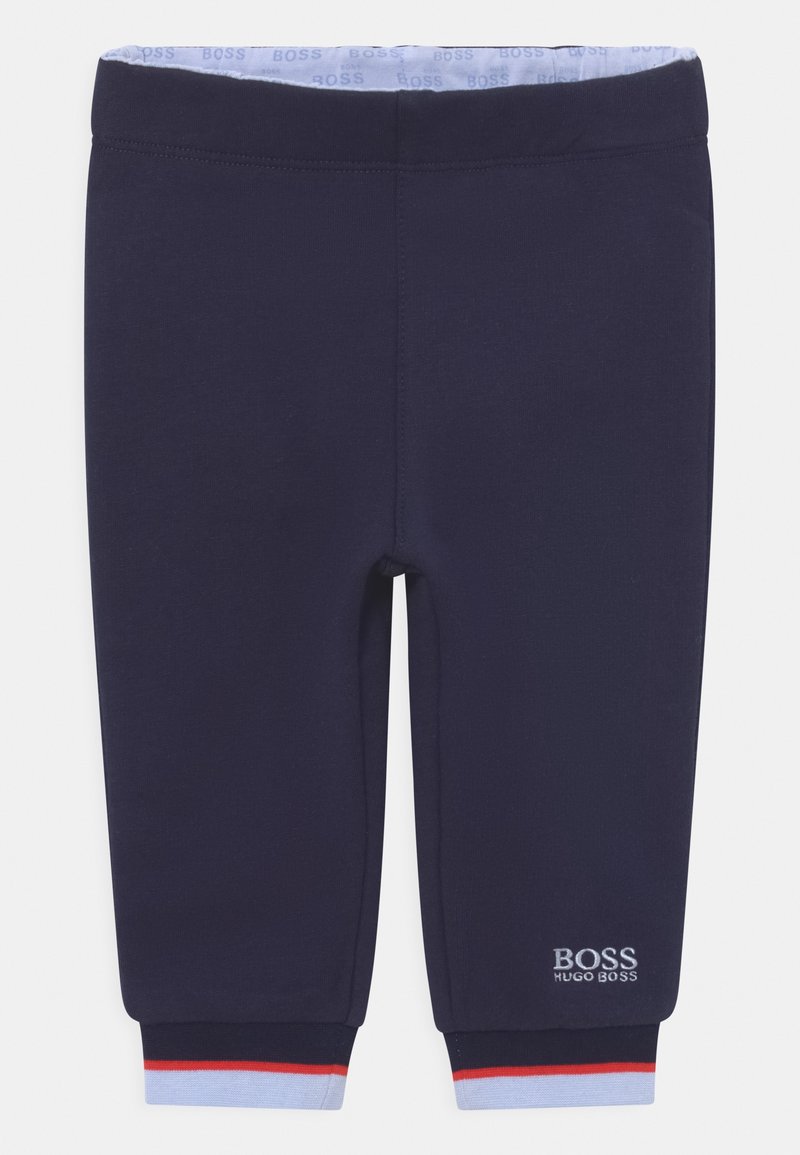 Joggeurs pour bébé bleu marine avec taille élastique, doublure intérieure bleu clair, poignets rayés rouge et bleu clair, et logo blanc Hugo Boss sur la jambe gauche.