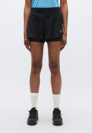 Czarne sportowe szorty z warstwową konstrukcją, elastycznym pasem i odblaskowym logo. Do tego białe skarpety za kostkę i czarne sneakersy.