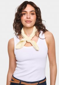 Sárga és fehér csíkos sál a nyak körül megkötve. Sima anyag, könnyű textúra, négyzet alakú és finom fényű.