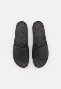 Svarte ortopedi sandaler med et teksturert vevd stropp, gummisåle og hevet logo på sålen, designet for komfort og enkelhet i bruk.