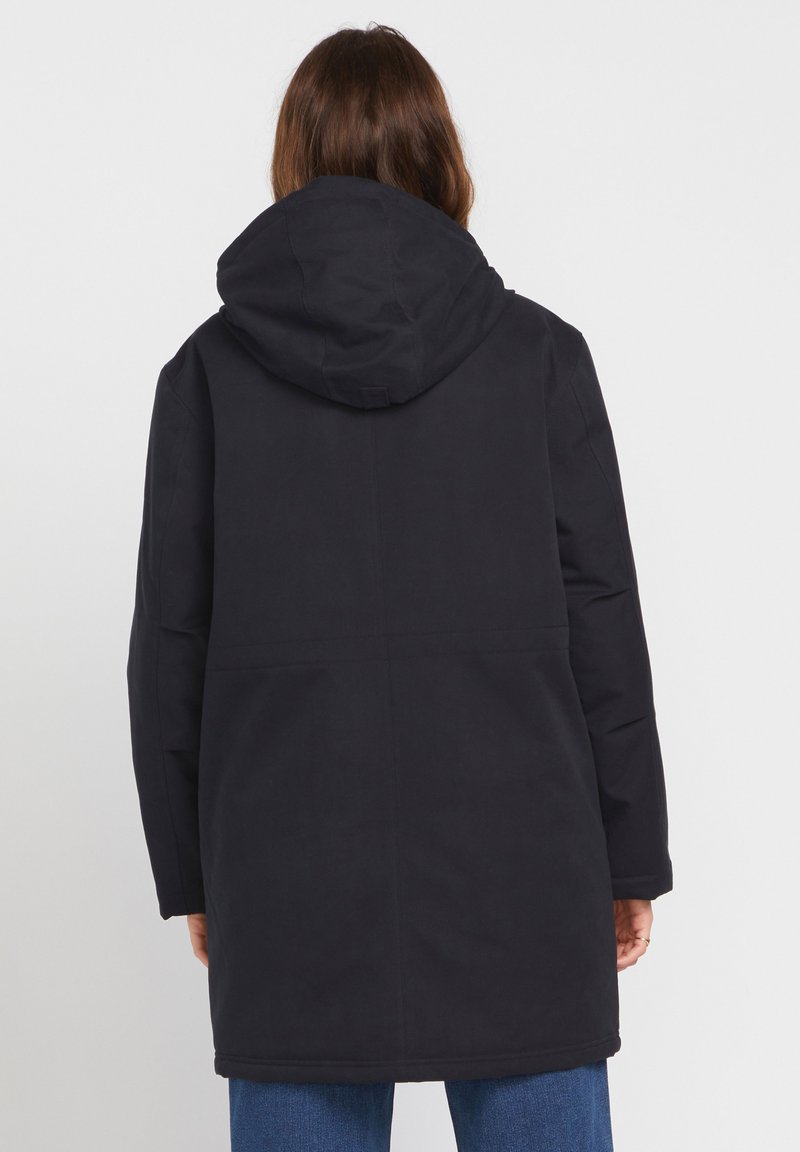 Cappotto nero con cappuccio e design di lunghezza media. Tessuto liscio, maniche lunghe e cuciture semplici per una finitura pulita.
