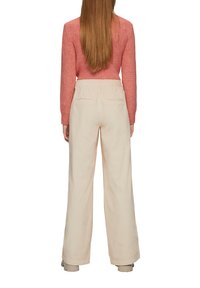 Crème-kleurige wijde broek van een gladde stof met achterzakken, gecombineerd met een gestructureerd, lang mouwtop in het pink.