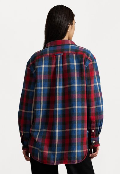Flannel shirt in red, blue, and black plaid pattern. Long sleeves, button cuffs, and a rounded hem with a back yoke detail.