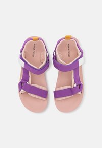 Violet sandaalit, joissa on säädettävät hihnat, kuvioitu sisäpohja ja vaaleanpunainen pohja. Sisältää keltaisen yksityiskohdan kantapäässä.