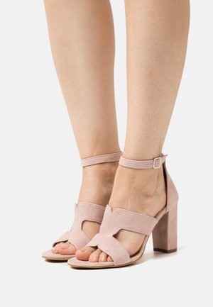 Sandales à talons en suede rose avec bout ouvert, design découpé, bride de cheville et talon bloc épais. Texture lisse et semelle intérieure rembourrée.