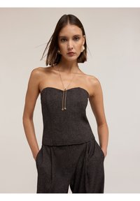 Top aderente senza spalline di colore grigio scuro, realizzato in tessuto testurizzato con una leggera lucentezza, dotato di scollatura dritta e collana decorativa in catena.