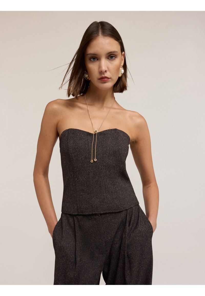 Top aderente senza spalline di colore grigio scuro, realizzato in tessuto testurizzato con una leggera lucentezza, dotato di scollatura dritta e collana decorativa in catena.