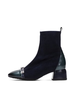 Botte noire en daim montant à la cheville avec embout et talon en cuir vert foncé, dotée d’un petit talon carré et d’une petite boucle décorative en argent près des orteils.