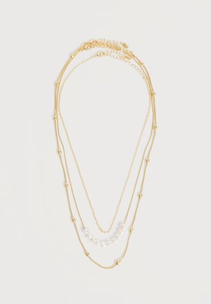 Trojsvrstvový náhrdelník v zlatej farbe s malými zlatými korálkami na dvoch retiazkach a bielymi perlami na najkratšom retiazke, zobrazený na bielom pozadí.