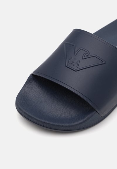 Tamno plavi sandale na klizanje s teksturiranom podlogom. Ima široku traku utisnutu logotipom, izrađenu od izdržljivog sintetičkog materijala.