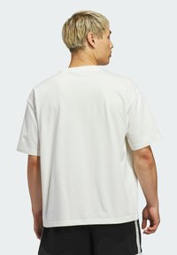 Biela bavlnená tričko s krátkymi rukávmi, okrúhlym výstrihom a voľným strihom. Hladká textúra, jednoduchý dizajn bez vzorov alebo akcentov.