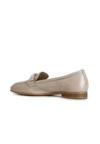Beige leren loafers met een lage hak, voorzien van een metallic gespdetail en een gladde textuur. Ronde neus en gestikte accenten.