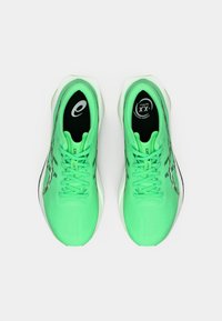 Par svetlo zelenih športnih čevljev za tek z črnimi notranjimi podplati, belimi srednjimi podplati in vezalkami, pogledano od zgoraj na beli podlagi.