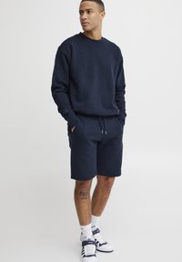 Marineblå sweatshirt og matchende shorts lavet af bomuldsblanding, med rund hals, lange ærmer og elastisk talje, med sidelommer.