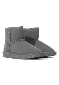 Botines de ante gris con punta redonda, que cuentan con tachuelas metálicas en un lado y una suela de goma texturizada para mayor agarre.