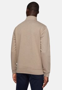 Sudadera beige con cuello alto, puños y dobladillo acanalados. Hecha de un tejido suave con una textura lisa, sin patrones ni logotipos visibles.