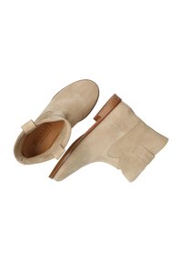 Botines de ante beige hasta el tobillo con punta redonda, tacón bajo de madera y una pestaña para facilitar el calzado. Presentan costuras sutiles y una etiqueta de marca en el tacón.