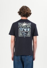 Black cotton t-shirt featuring a colorful, geometric landscape graphic on the back, with mountains, cacti, and the word "Quiksilver" centered below.