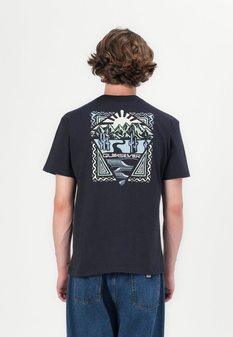 Black cotton t-shirt featuring a colorful, geometric landscape graphic on the back, with mountains, cacti, and the word "Quiksilver" centered below.