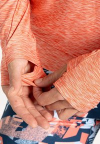 Sportlicher Langarmoberteil in leuchtendem Orange mit strukturiertem, meliertem Muster. Verfügt über Daumenöffnungen in den Bündchen und zeigt ein enganliegendes Design.