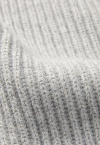 Tessuto a maglia grigia a coste, realizzato in morbida lana, con una fine trama caratterizzata da linee verticali in rilievo e delicati granelli di grigio scuro.