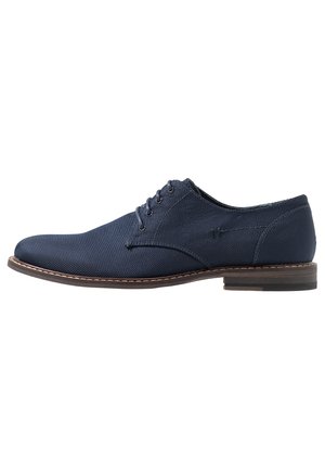Navyblauwe herenschoen met veters, Oxford-model, met een gestructureerde stof bovenkant en een bruine zool, zijaanzicht op een witte achtergrond.