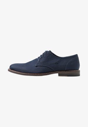 Zapato Oxford de hombre en azul marino con cordones, parte superior de tela texturizada y suela marrón, mostrado de perfil sobre fondo blanco.