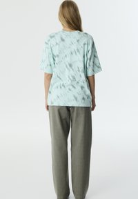 Camiseta tie-dye verde menta hecha de tela suave con un ajuste holgado, combinada con pantalones grises sueltos, mostrando un estilo cómodo y casual.