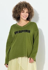 Blusa de manga larga verde oliva con escote en V y dobladillo curvado. Presenta "INSPIRE" en lentejuelas negras en el pecho. Tela suave, corte relajado.