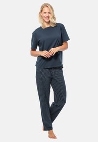 T-shirt en coton bleu marine associé à un pantalon de pyjama avec des pois bleu marine ; coupe décontractée, manches courtes, texture douce et ceinture élastique.