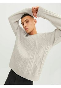 Light gray knitted sweater featuring textured diamond and cable patterns, ribbed cuffs, and a round neckline. Relaxed fit design.