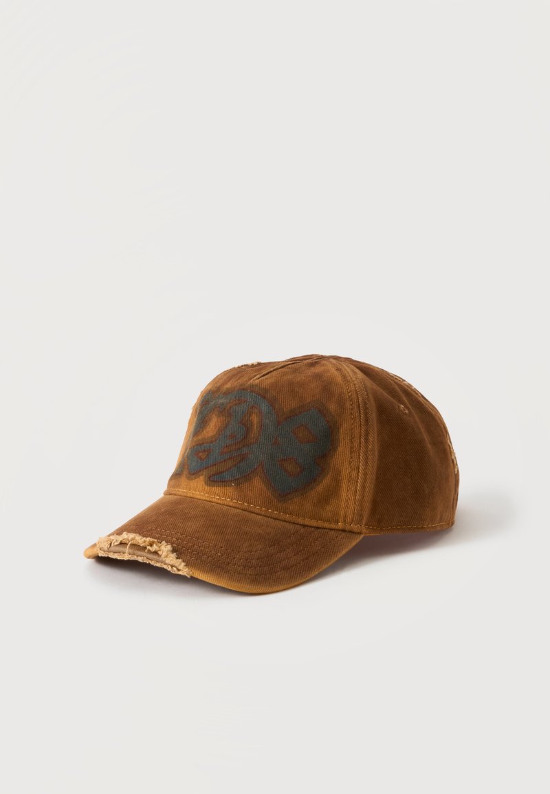 Casquette de baseball marron usée avec un motif style graffiti noir sur la partie avant, présentée sur fond blanc.